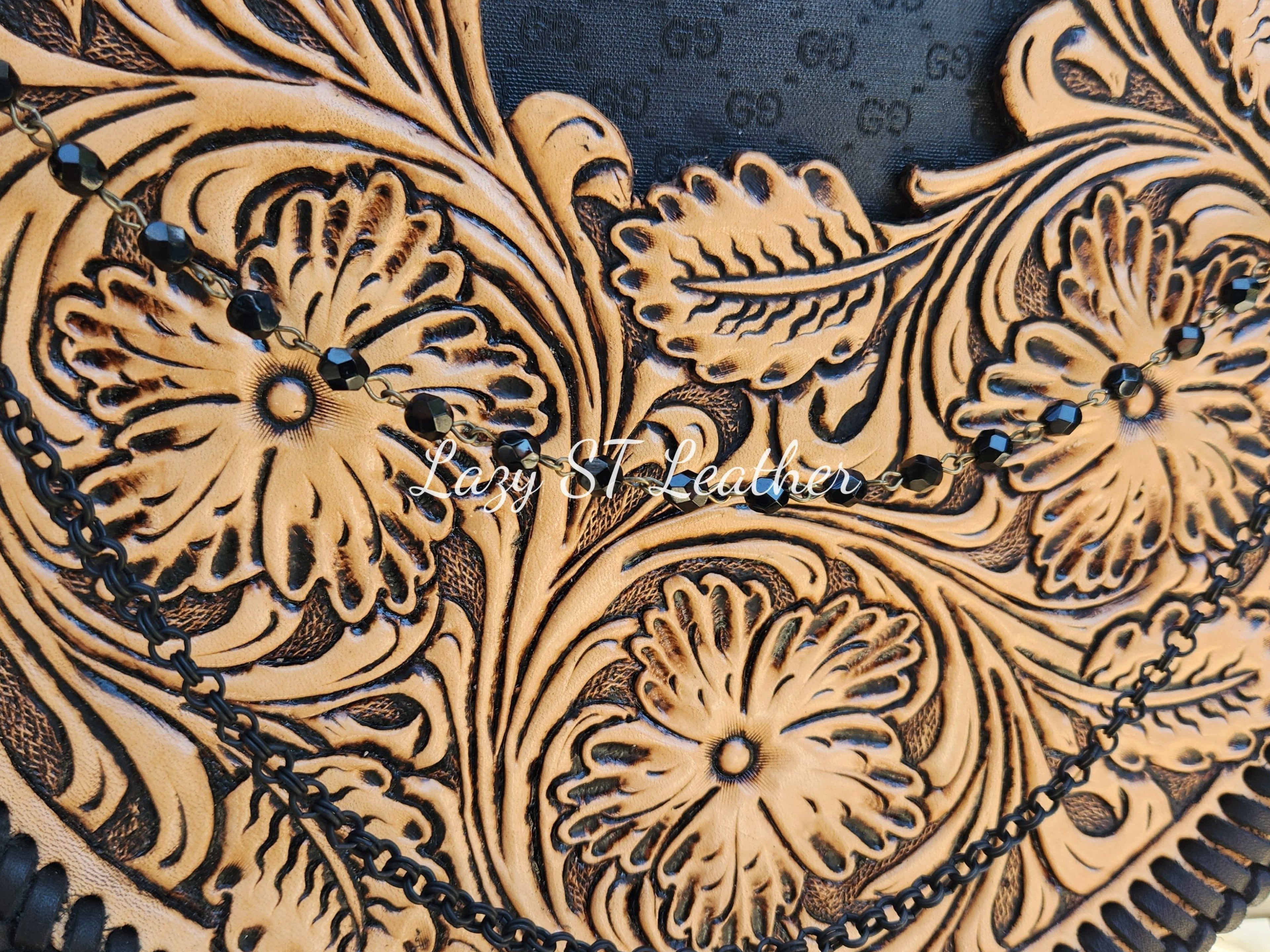 Close-up of a leather product with intricate floral patterns and black beads.